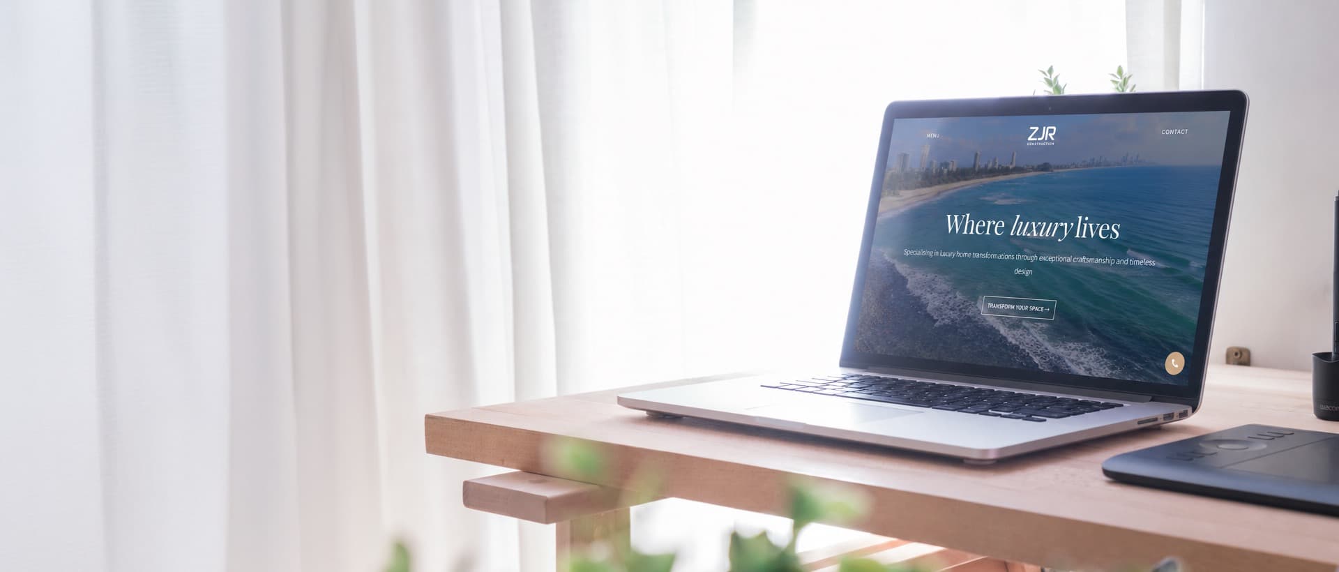 A sunlit desk with an open laptop showing a client website